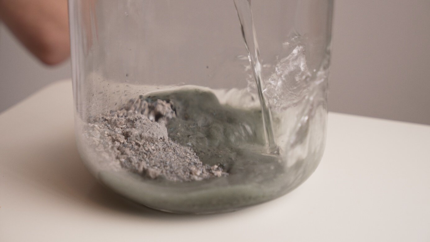 Pflanzenasche wird mit Quellwasser gelöst